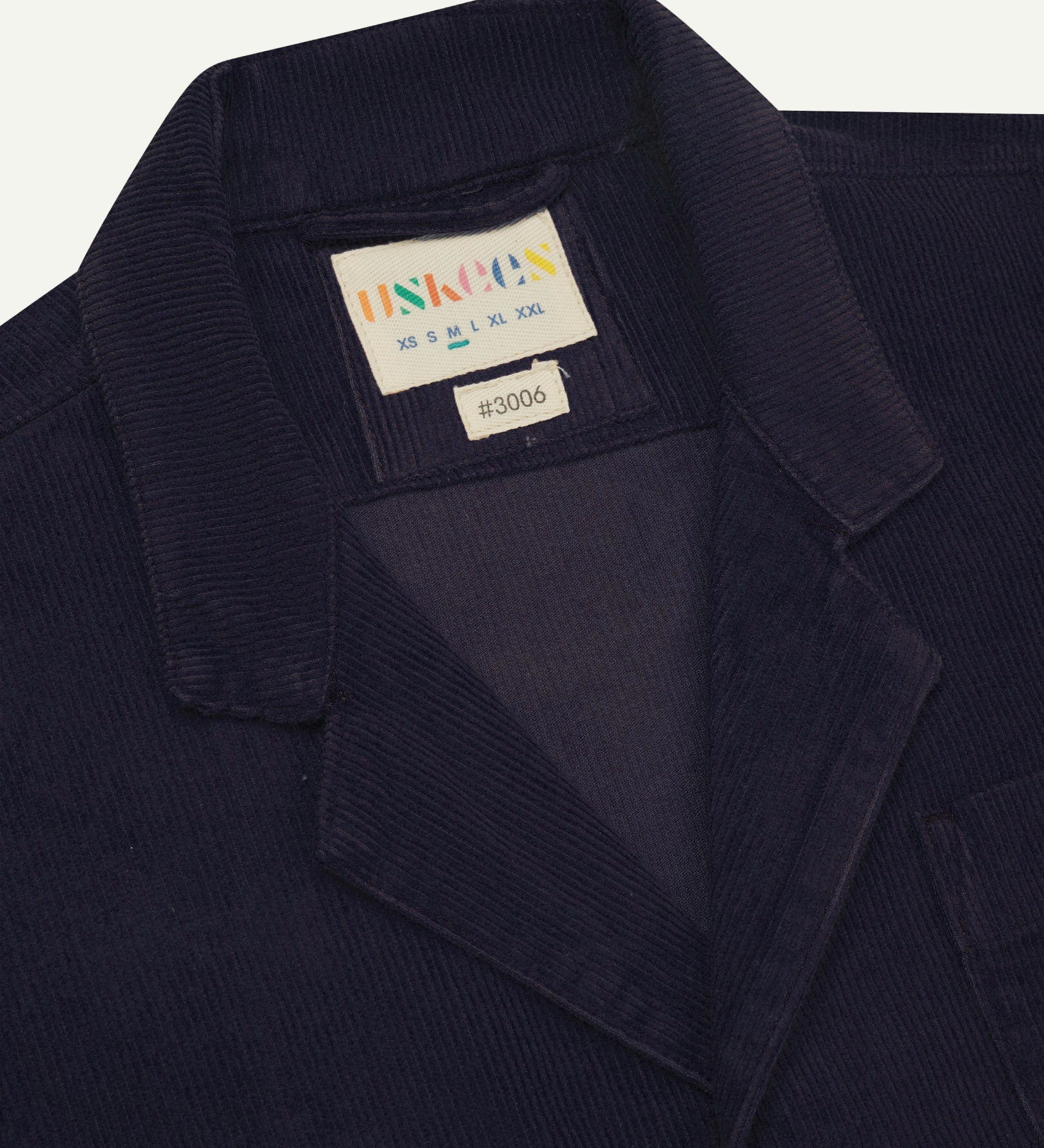 Close-up front view of organic cord midnight blue blazer showing the collar, lapels and Uskees brand label.