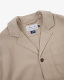 Angled top-half view of #3006, oatmeal (beige) organic cotton-drill blazer. With focus on collar, notch lapels, breast pocket, Uskees brand label and corozo buttons.