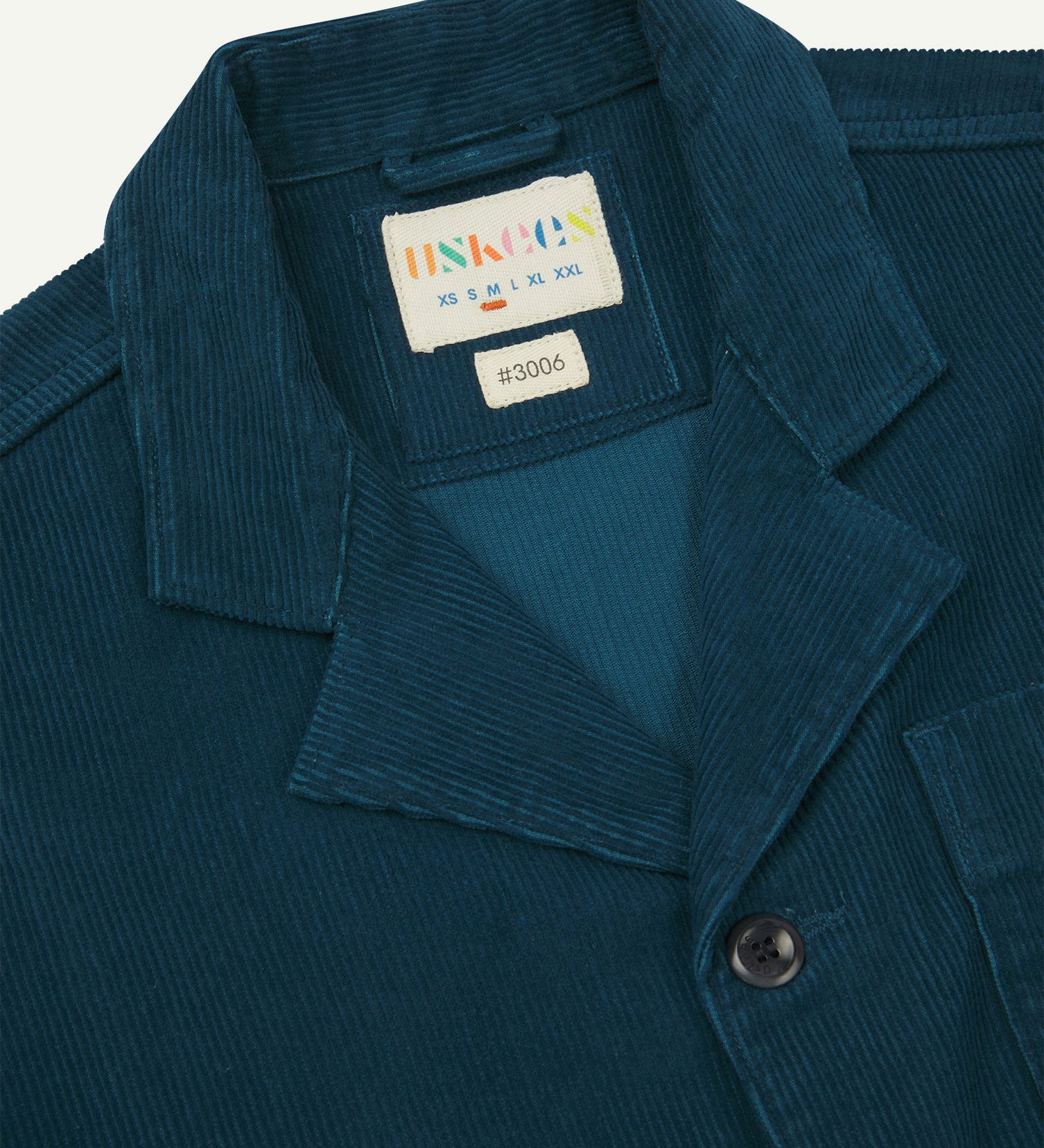 Close-up front view of organic cord petrol blue blazer showing the collar, lapels and Uskees brand label.