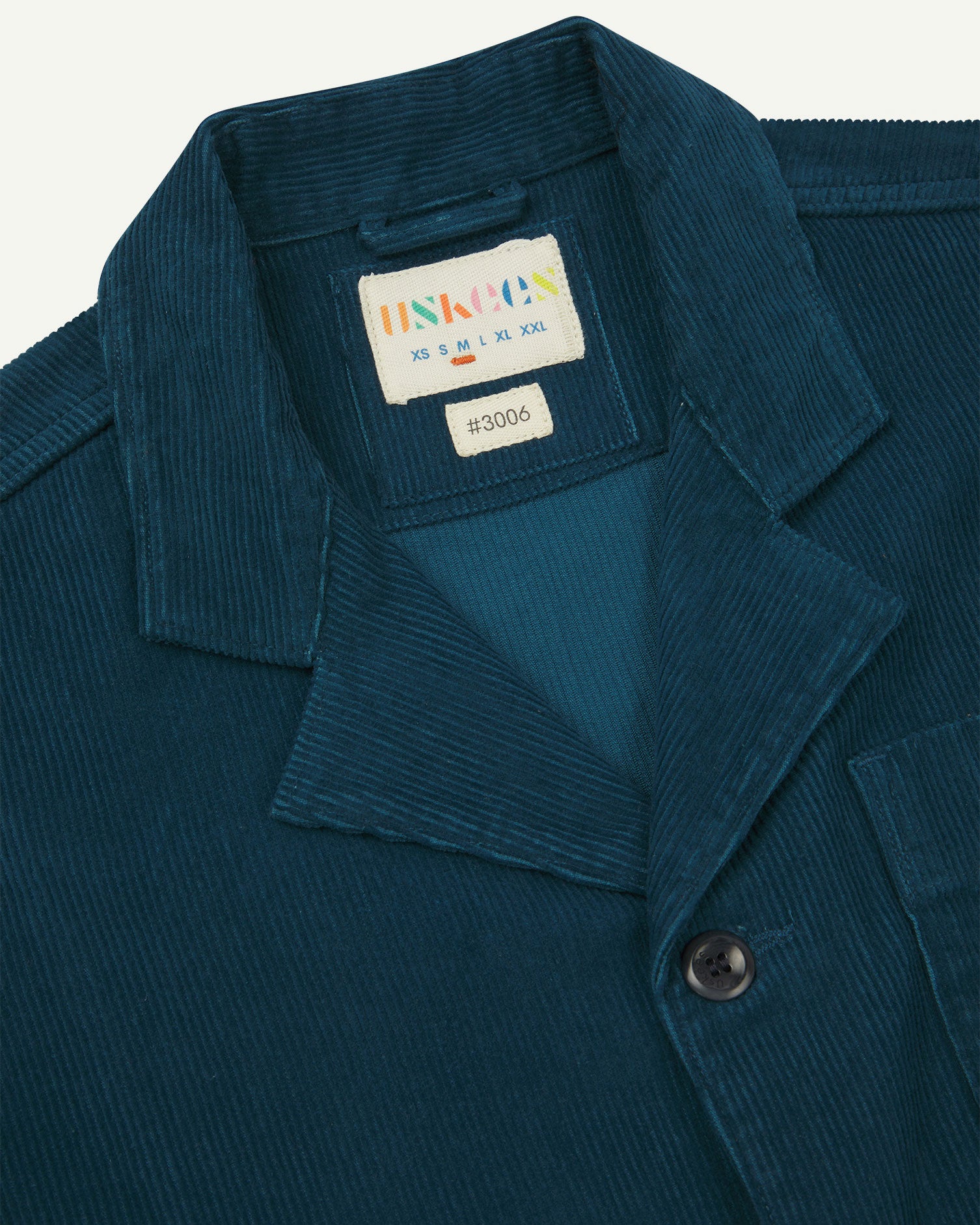 Close-up front view of organic cord petrol blue blazer showing the collar, lapels and Uskees brand label.