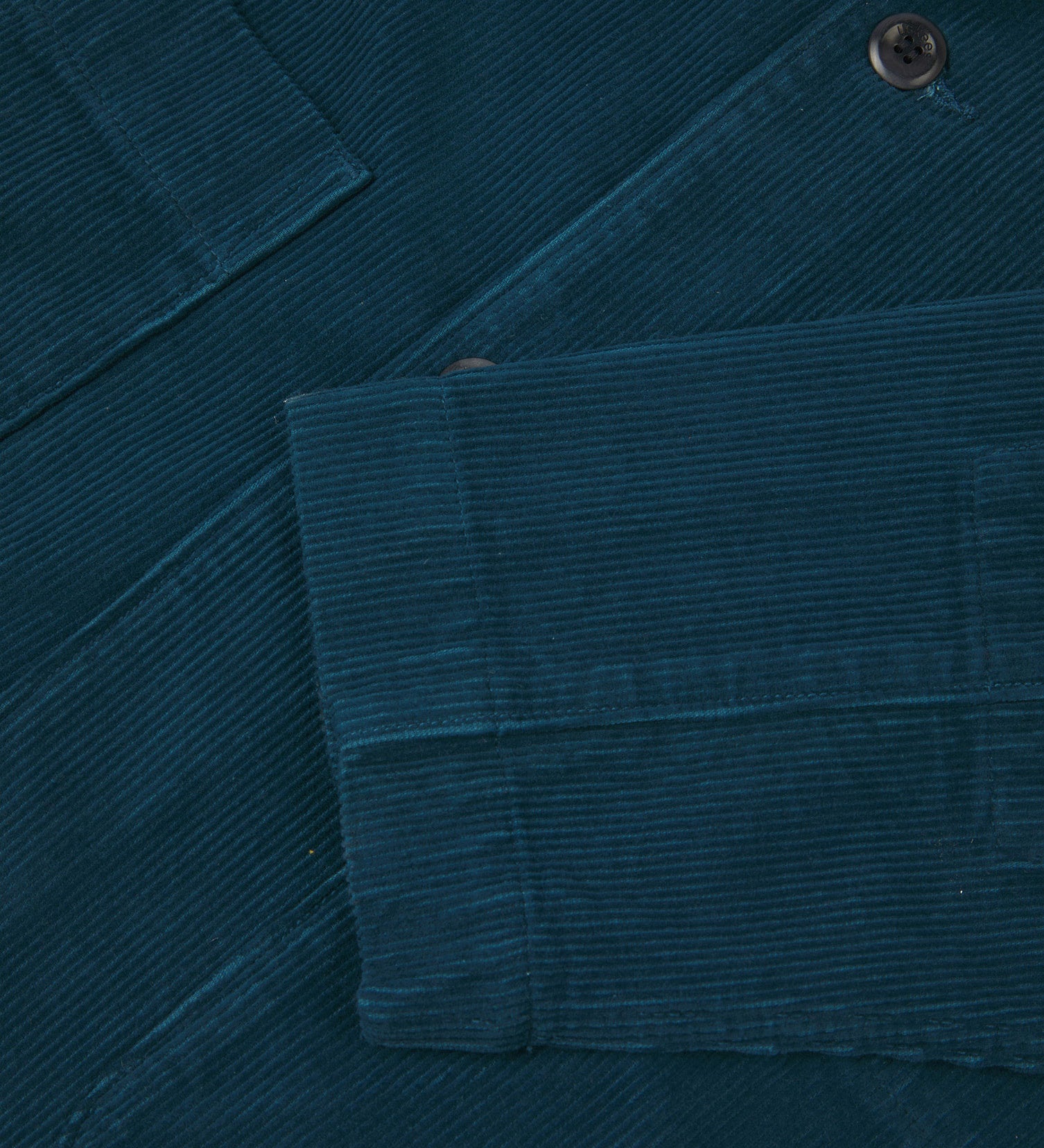 Close-up view of cuff, placket and corozo buttons of organic corduroy, petrol blue blazer from Uskees.