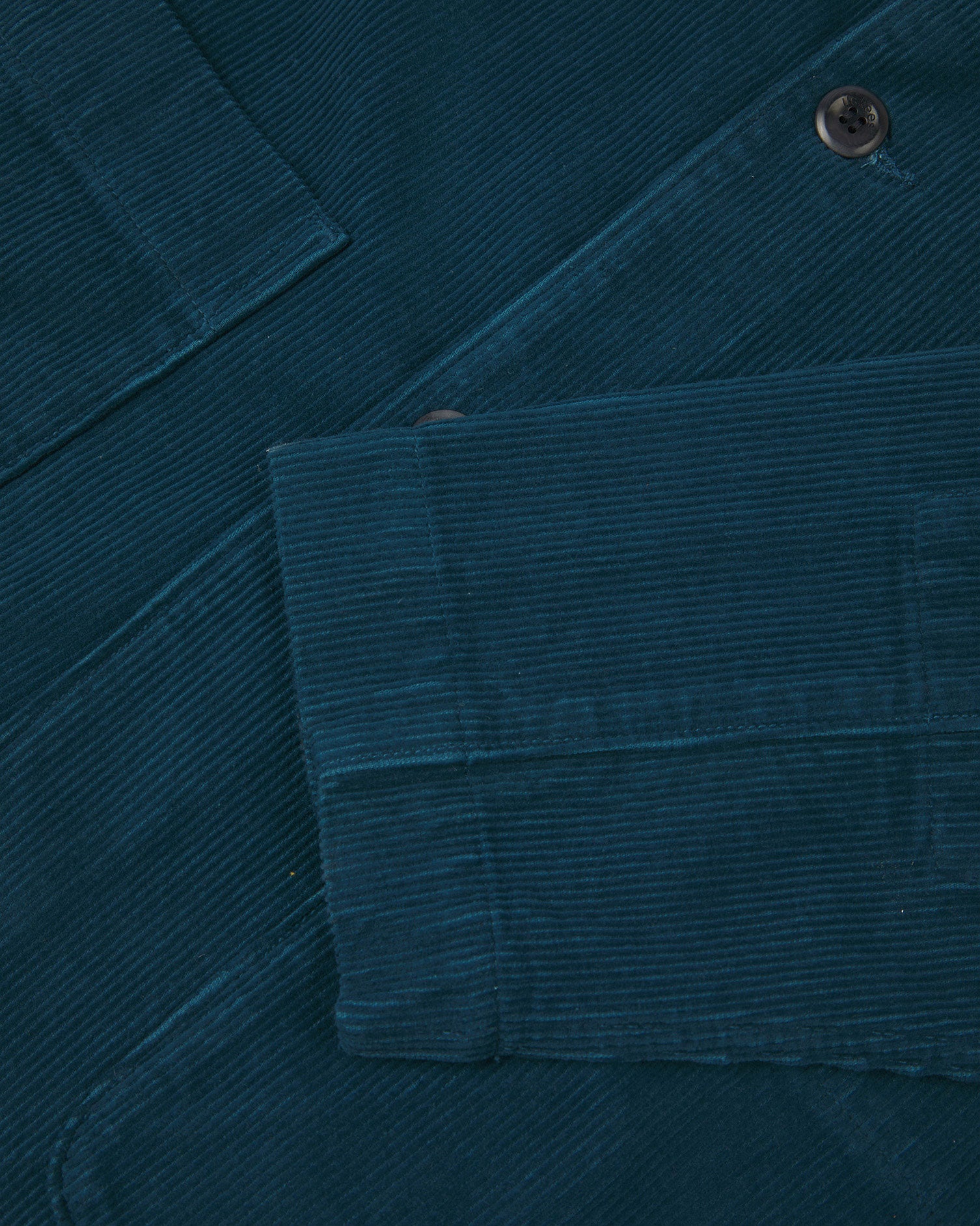 Close-up view of cuff, placket and corozo buttons of organic corduroy, petrol blue blazer from Uskees.