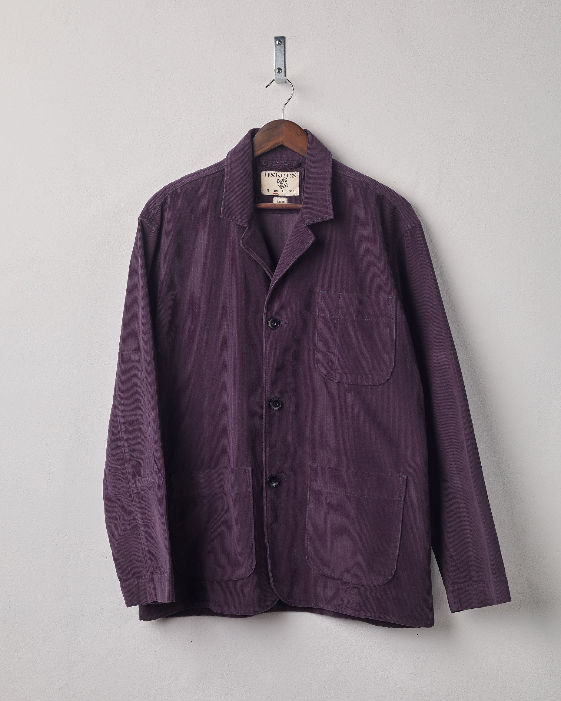 Front view of plum corduroy blazer with 3 patch pockets from Uskees. Presented on a hanger.