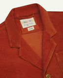 Close-up front view of organic cord rust-red blazer showing the collar, lapels and Uskees brand label.