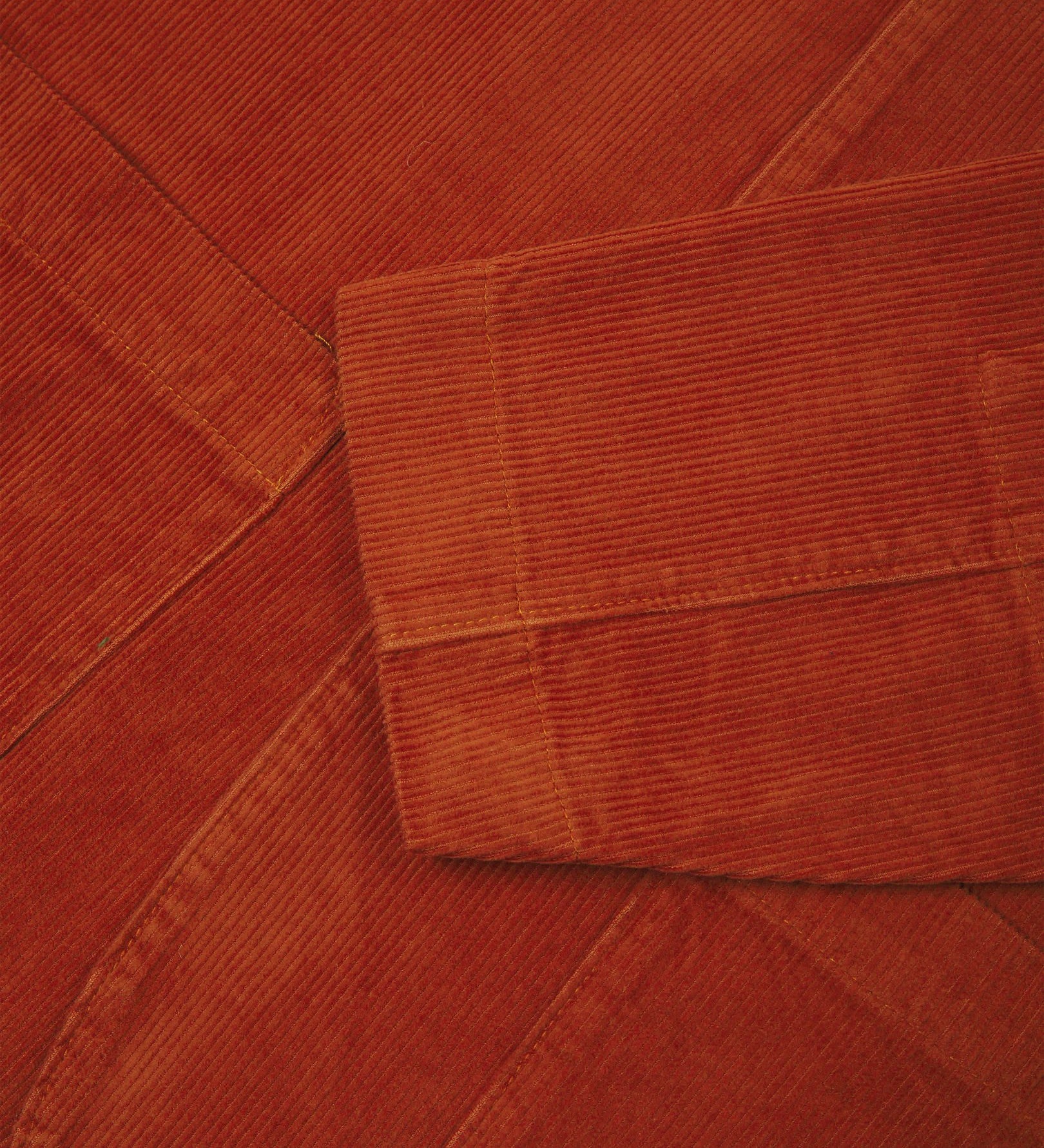 Close-up view of cuff, placket and corozo buttons of rust-red blazer from Uskees and providing a clearer view of the 11 wale organic corduroy.