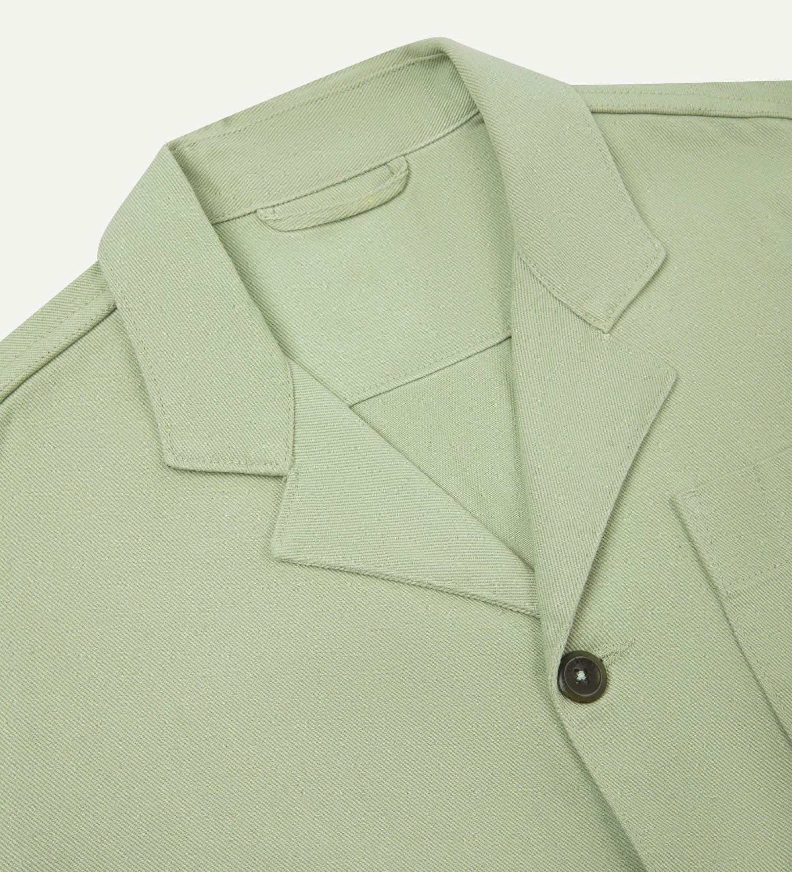 Close-up top-half view of #3006, silver-green organic cotton-drill blazer. With focus on collar, lapels and corozo buttons.