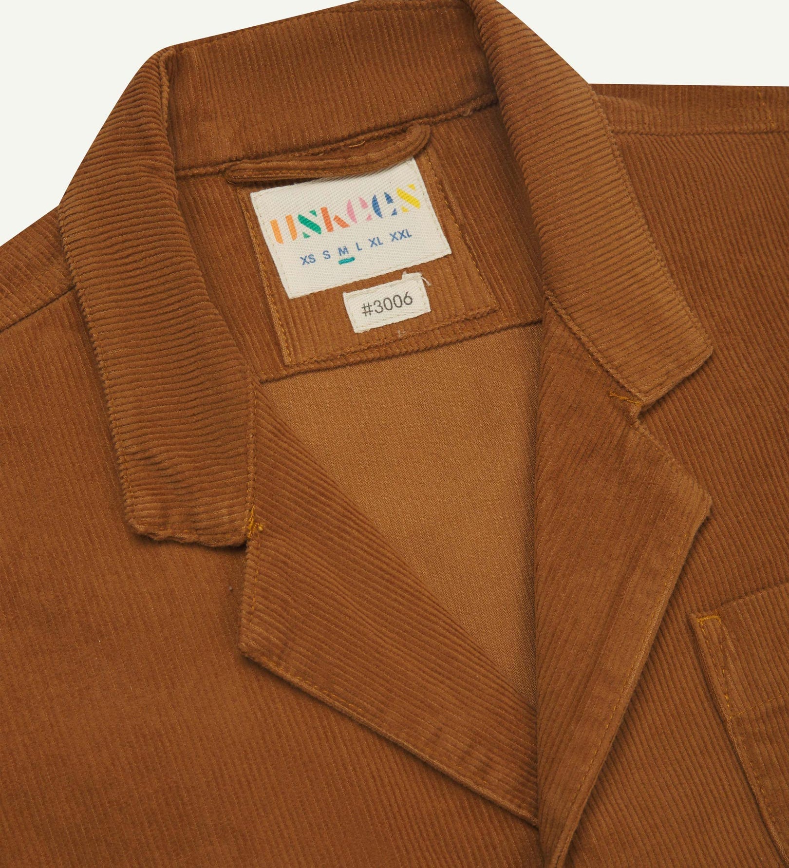 Close-up front view of organic cord tan blazer showing the collar, lapels and Uskees brand label.