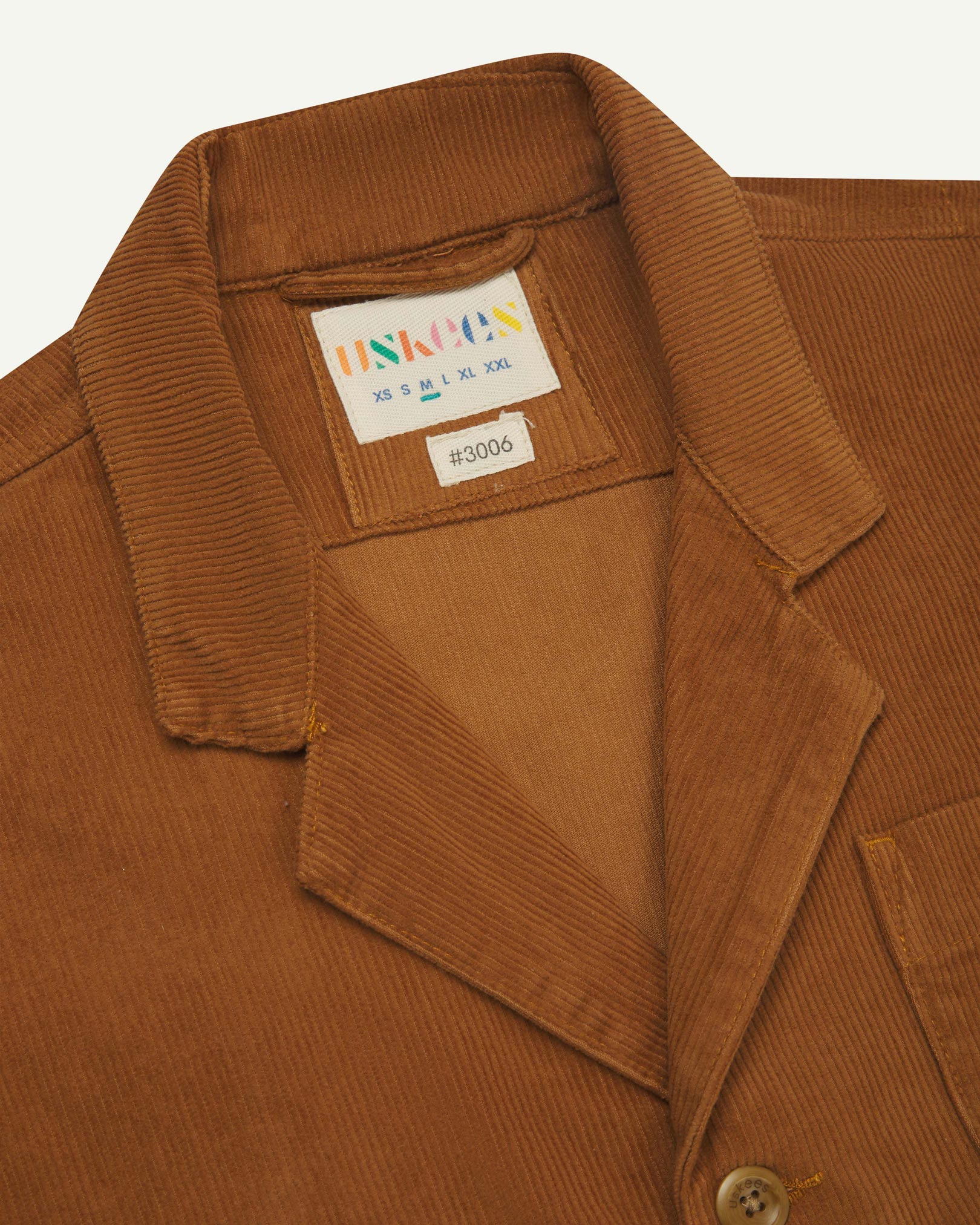 Close-up front view of organic cord tan blazer showing the collar, lapels and Uskees brand label.