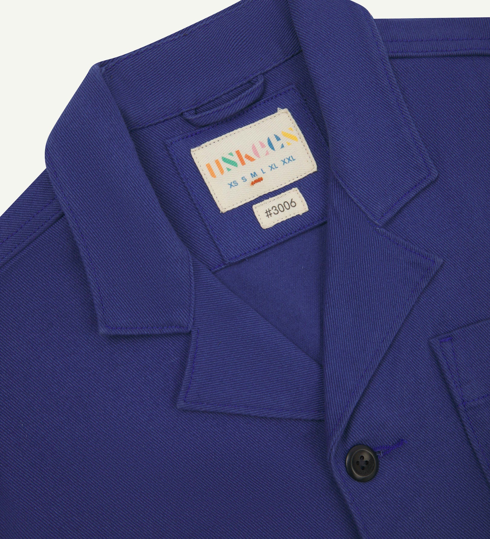 Close-up top-half view of #3006, ultra blue organic cotton-drill blazer. With focus on collar, lapels, Uskees brand label and corozo buttons.