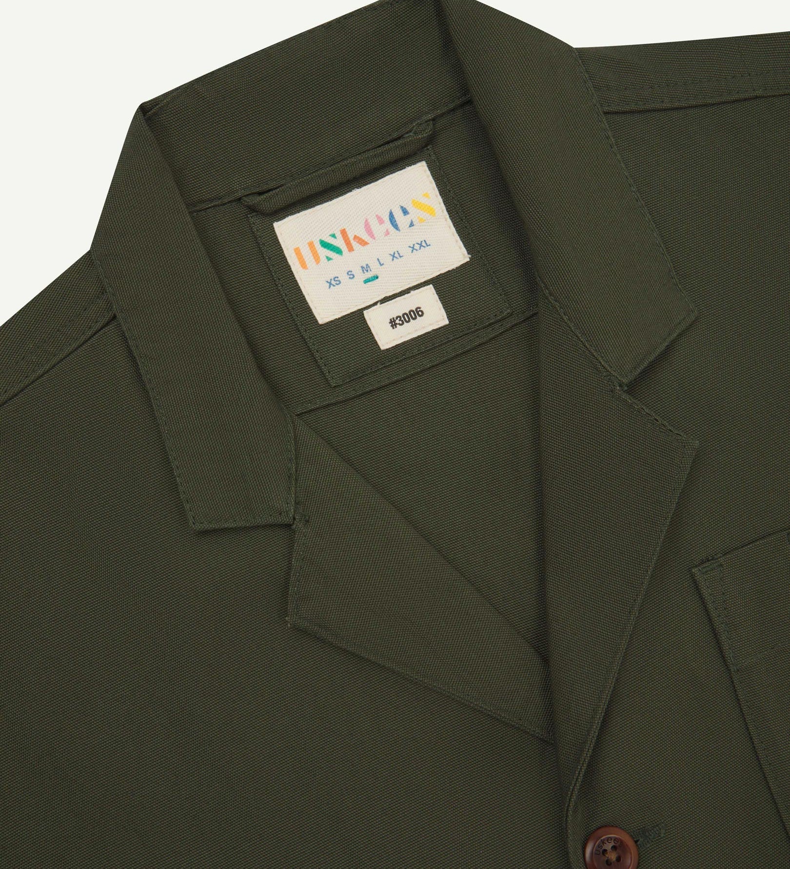 Close-up front view of organic cotton vine green blazer showing the collar, lapels and Uskees brand label.