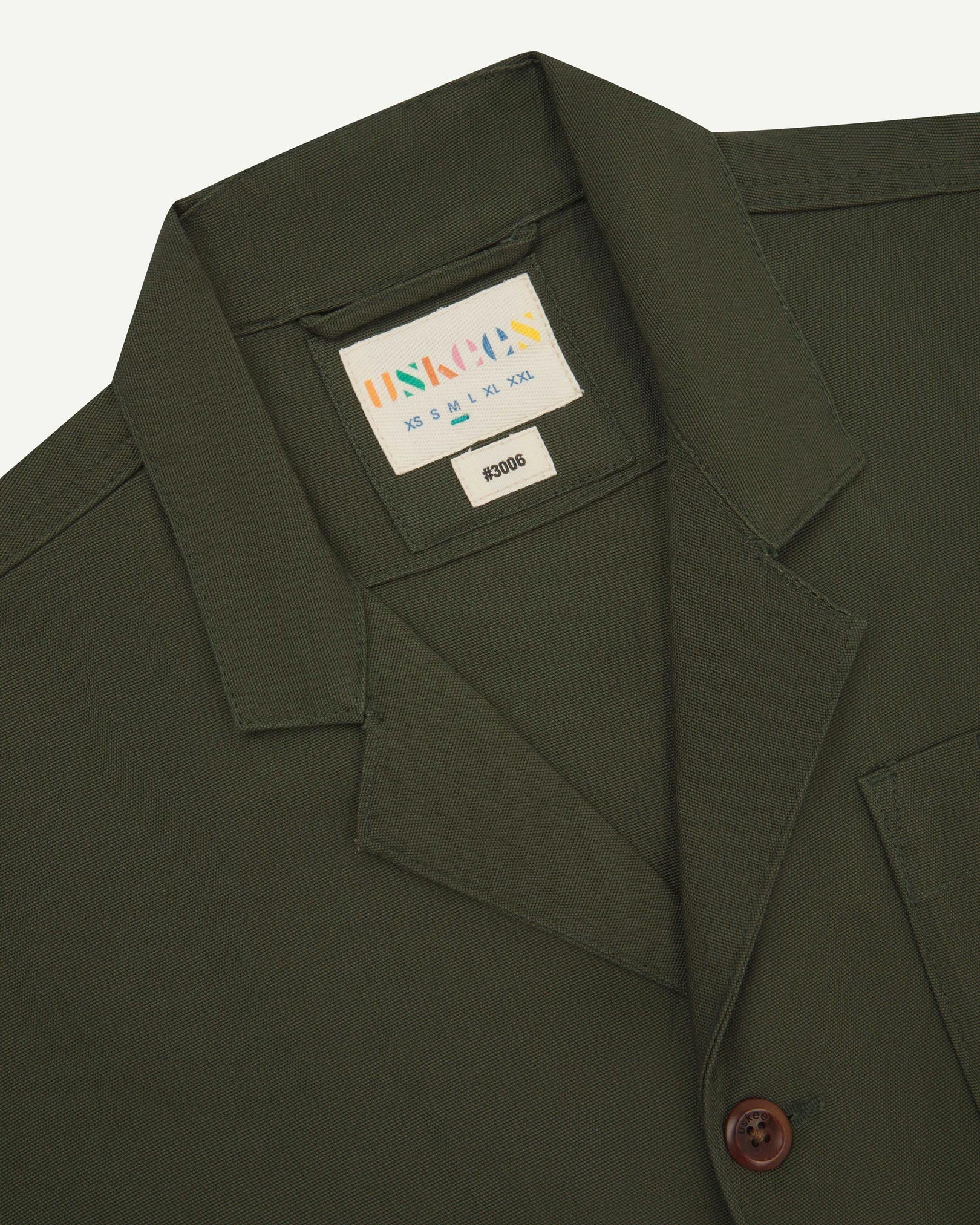 Close-up front view of organic cotton vine green blazer showing the collar, lapels and Uskees brand label.