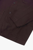 Close-up of a dark plum jacket with visible Corozo buttons and cuff details, photographed against a plain white background.