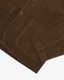 Close up view of Uskees brown cord men's jacket showing the front pocket and sleeve detail on a white background.
