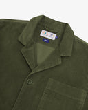 Close up flat shot of Uskees dark green men's cord jacket showing the collar and brand label at neck.