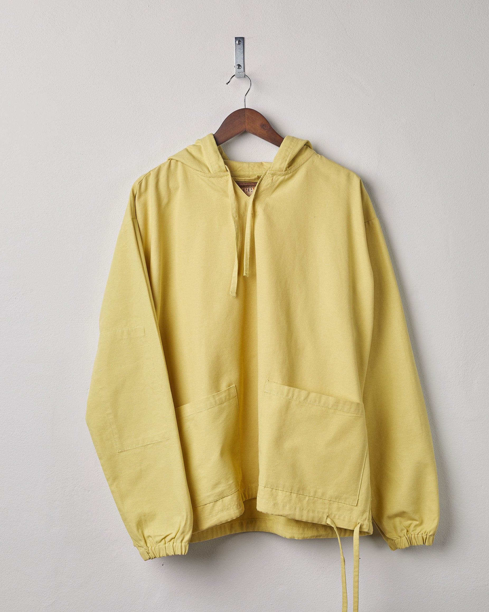 Full-length front view of 'lime' coloured smock from Uskees presented on hanger.