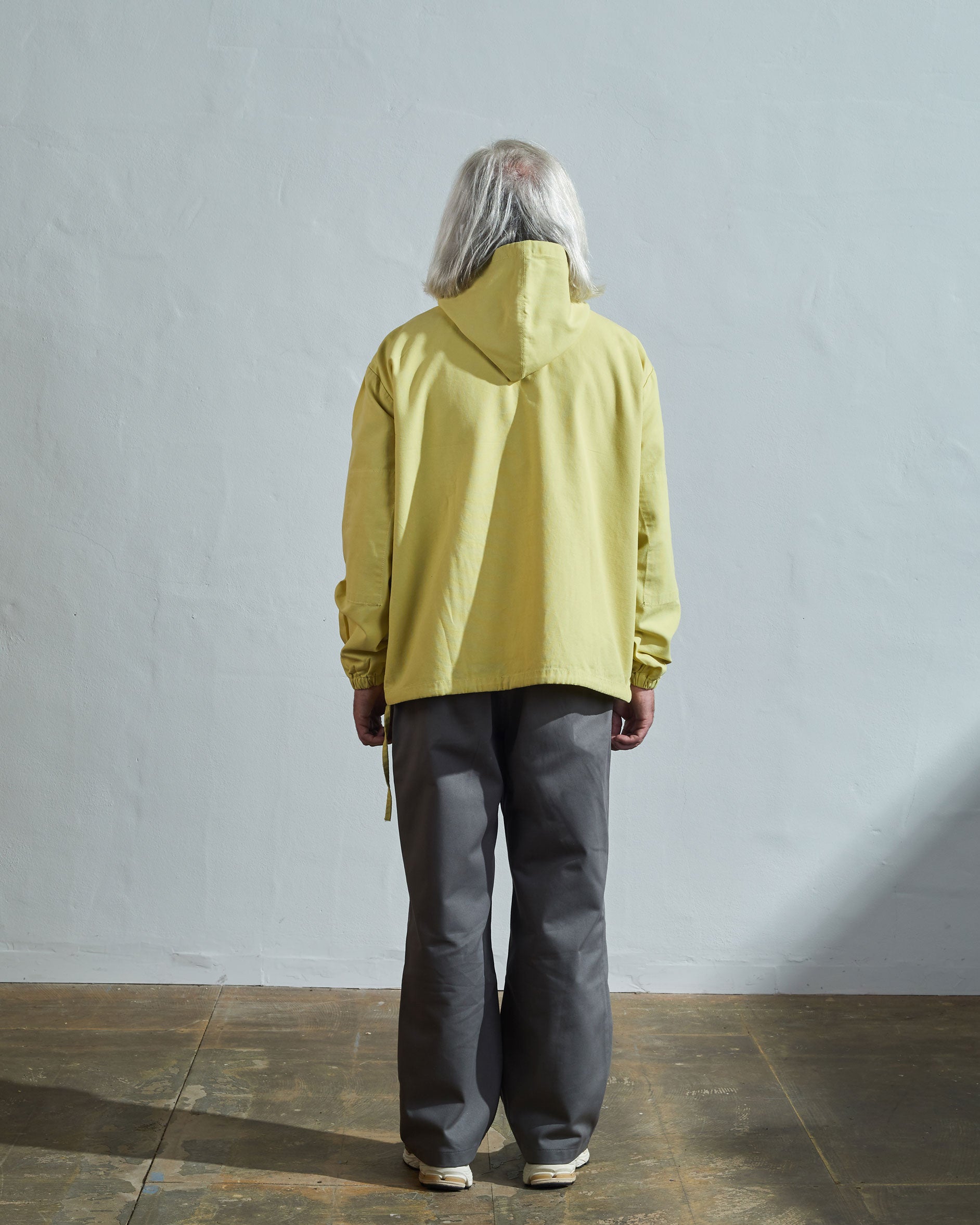 Full-length rear view of model wearing Uskees smock in pale yellow organic cotton.
