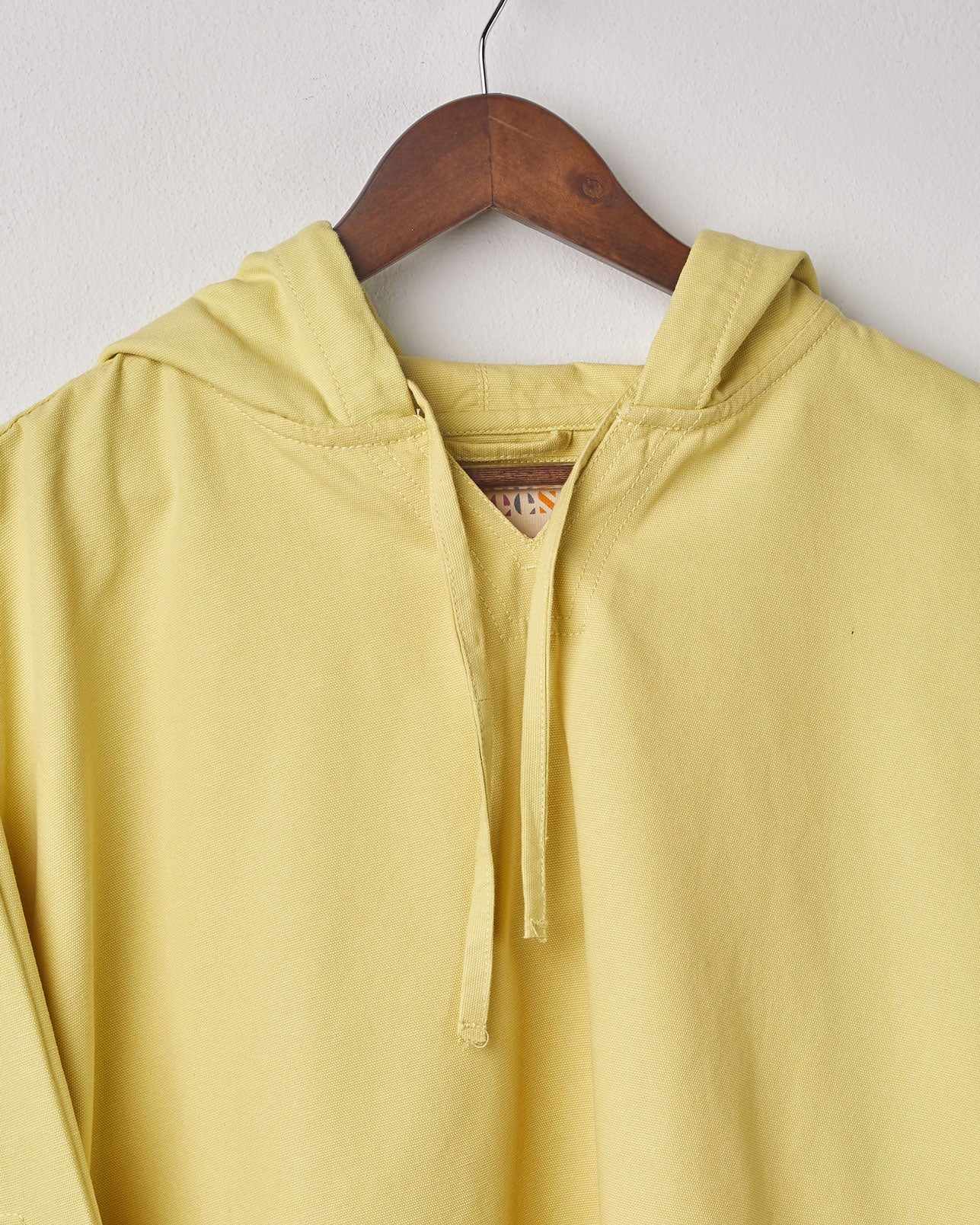 Close-up top view of #3008 smock from Uskees in lime showing the neckline and drawstring hood.