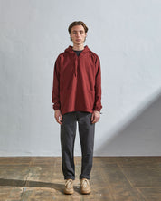 Full-length front view of model wearing Uskees smock in merlot-coloured organic cotton, paired with charcoal-grey pants.