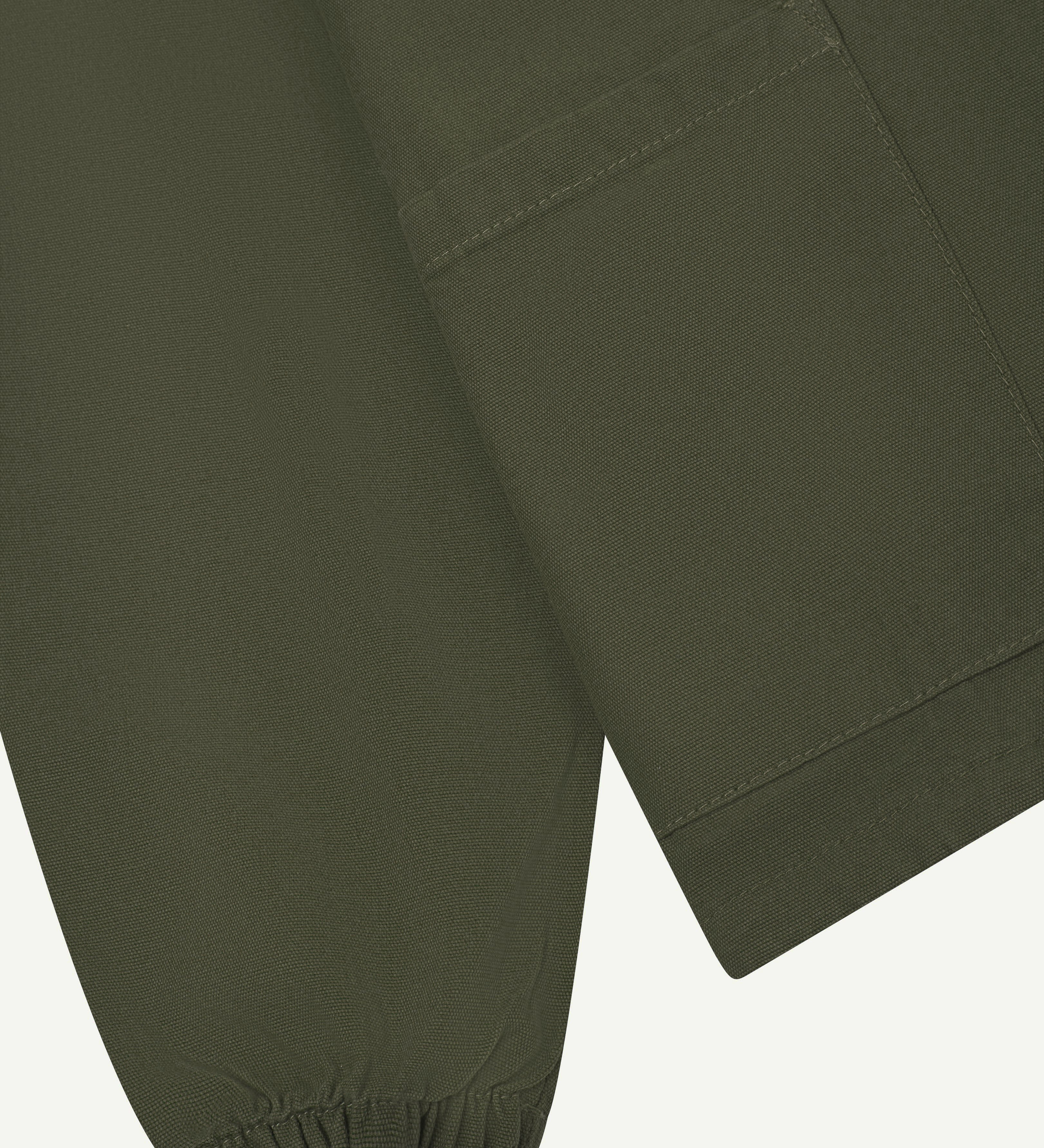 Close detail shot of uskees dark green men's organic cotton smock showing elasticated cuff & front pocket