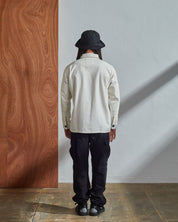 Full-length back model shot of Uskees #3011 cream Overshirt. Paired with cream cargo pants and matching hat.