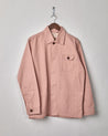 Front view Uskees covered button men's shirt jacket #3011 in dusty pink. Presented on a hanger with view of branding label, chest and hip pockets.