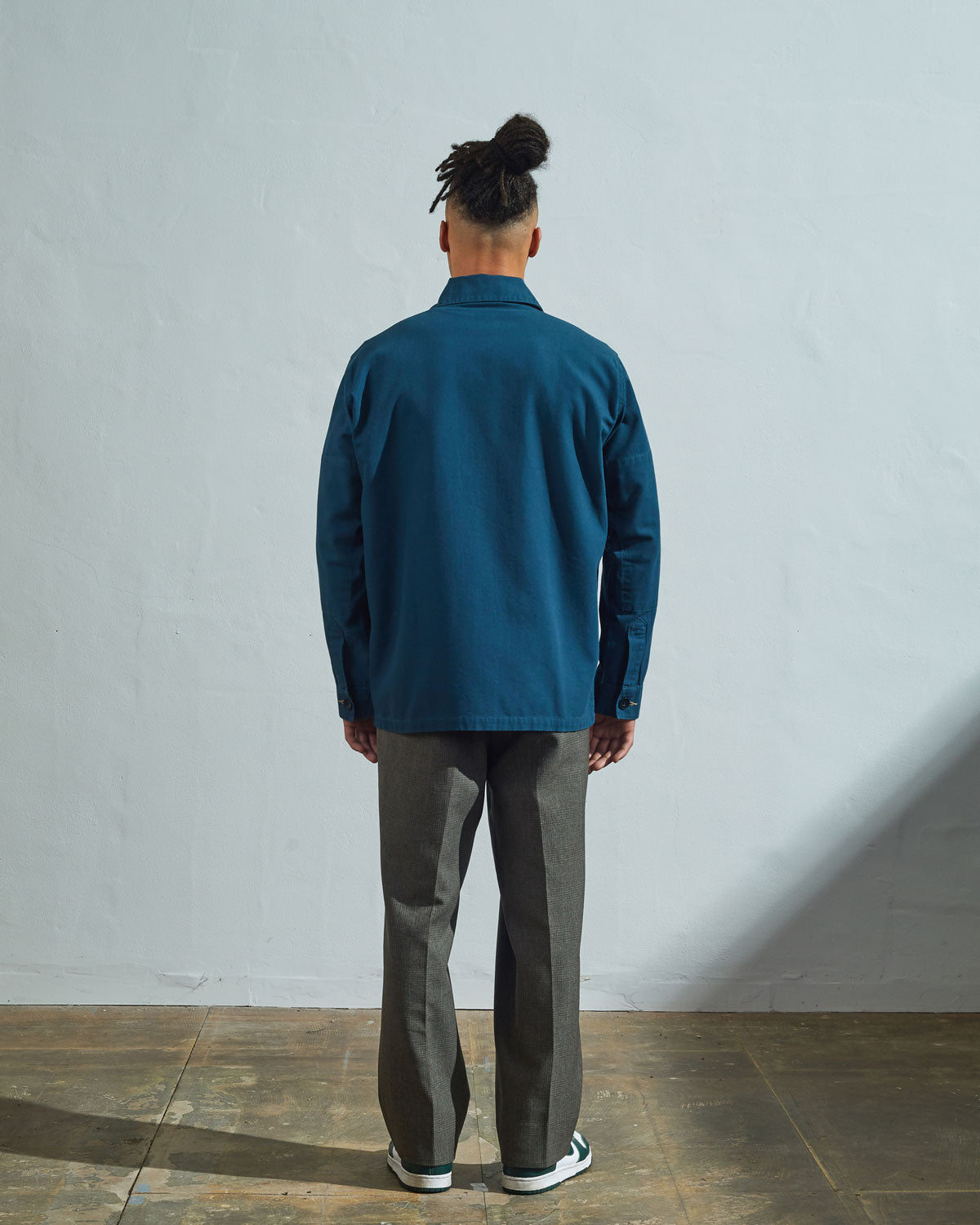 Back view of model wearing Uskees men's shirt jacket #3011 in peacock organic cotton showing reinforced elbows.
