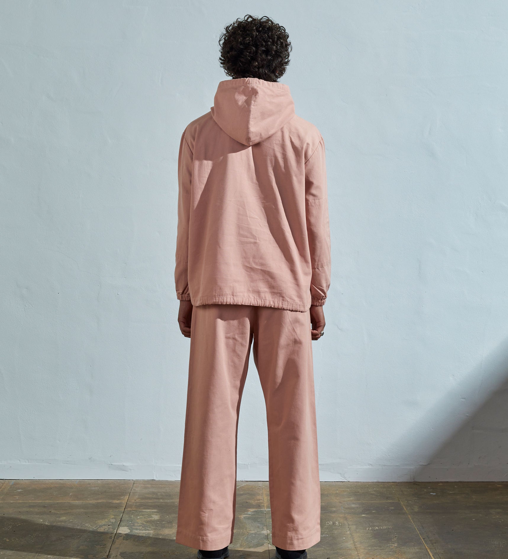 Full-length back view wearing Uskees 'dusty pink' coloured buttoned smock, with view of hood, reinforced elbows and boxy silhouette.