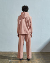 Full-length back view wearing Uskees 'dusty pink' coloured buttoned smock, with view of hood, reinforced elbows and boxy silhouette.