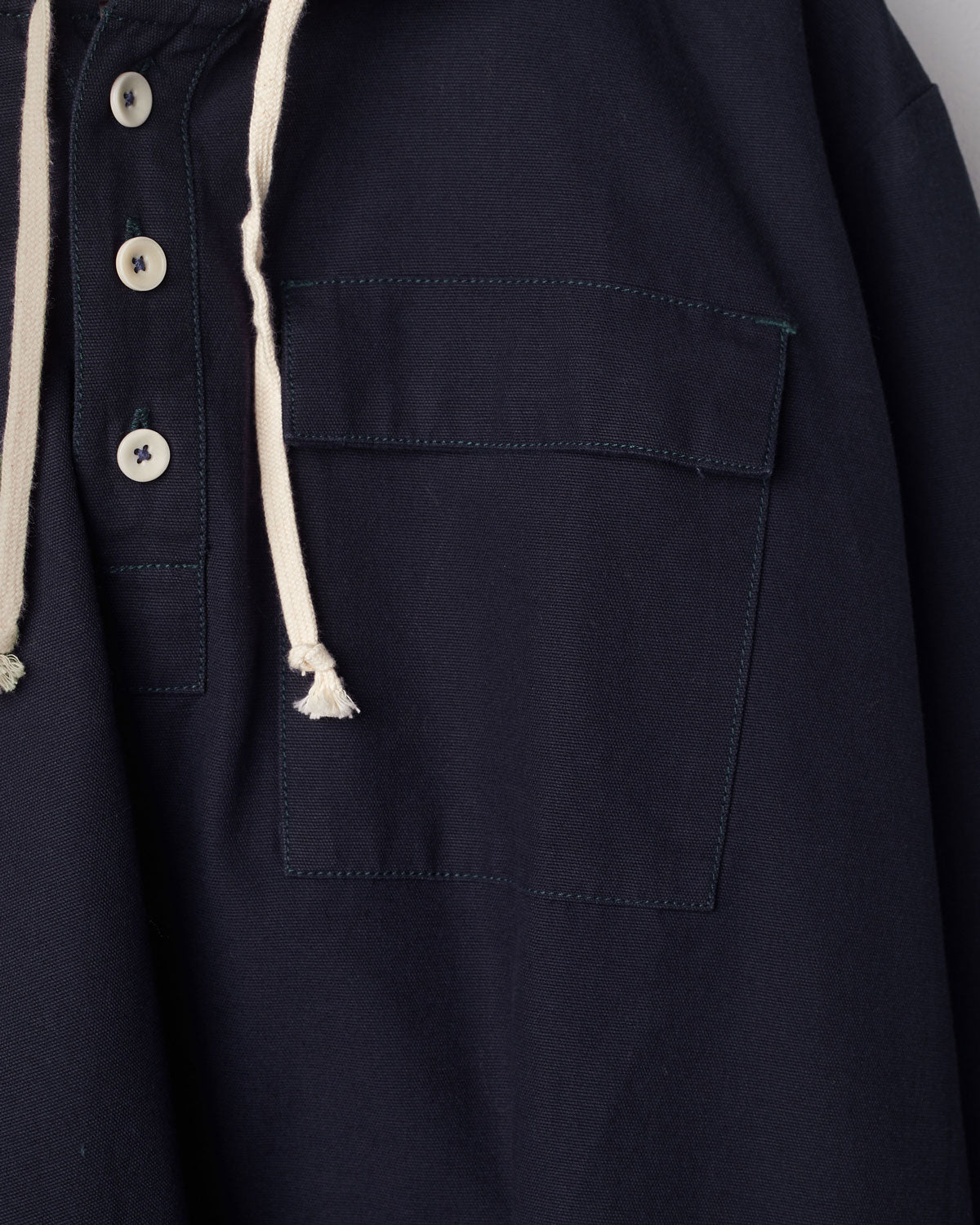 Close-up of midnight blue coloured buttoned smock from Uskees with focus on right breast pocket.