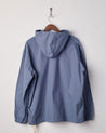Back view of teal coloured buttoned smock from Uskees with view of hood. Presented on hanger with white backdrop.