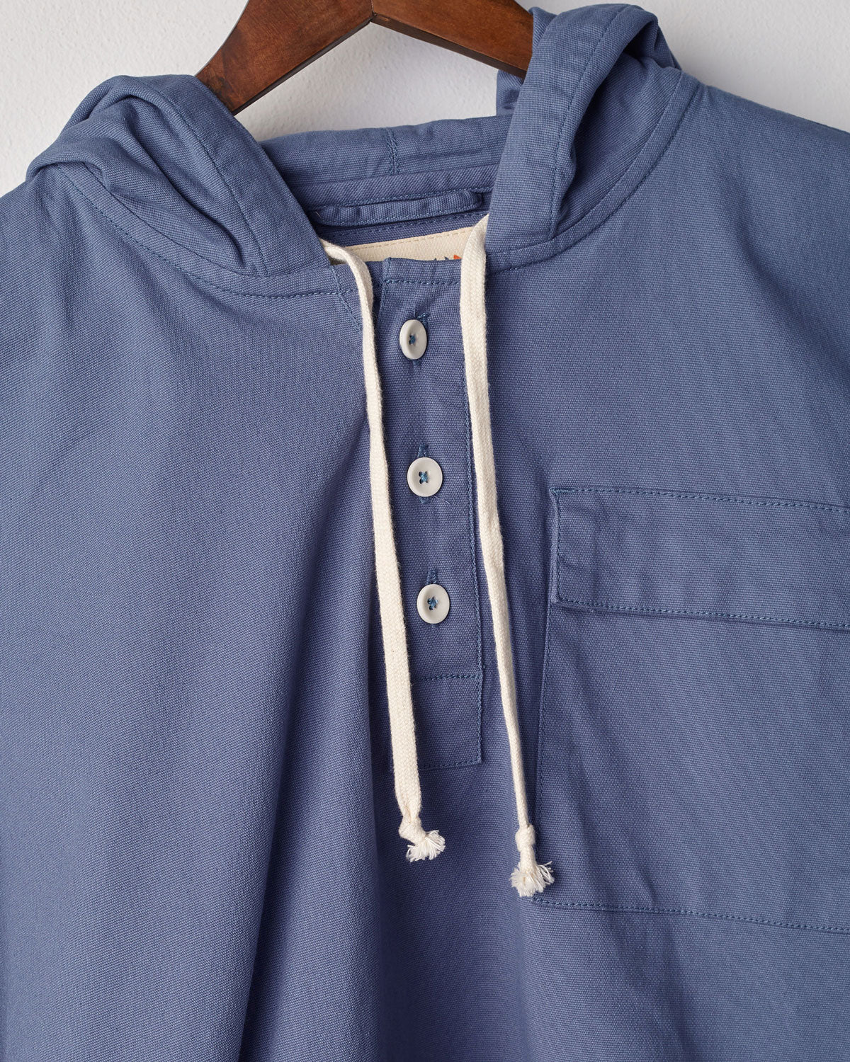 Closer front view of Uskees teal smock with focus on front buttons, neck drawstring and breast pocket.