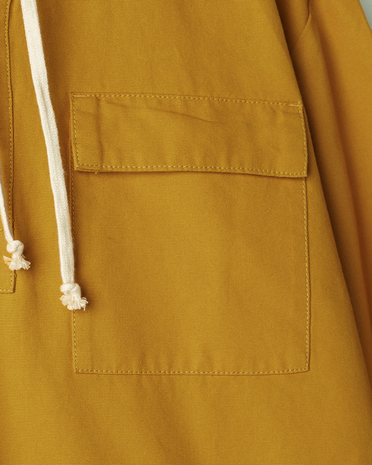 Close-up of yellow coloured buttoned smock from Uskees with focus on right breast pocket.
