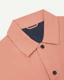 Neck view of Uskees 3013 pink-orange (coral) organic cotton coach jacket with focus on collar, contrast inner yoke, Uskees brand label and popper buttons.