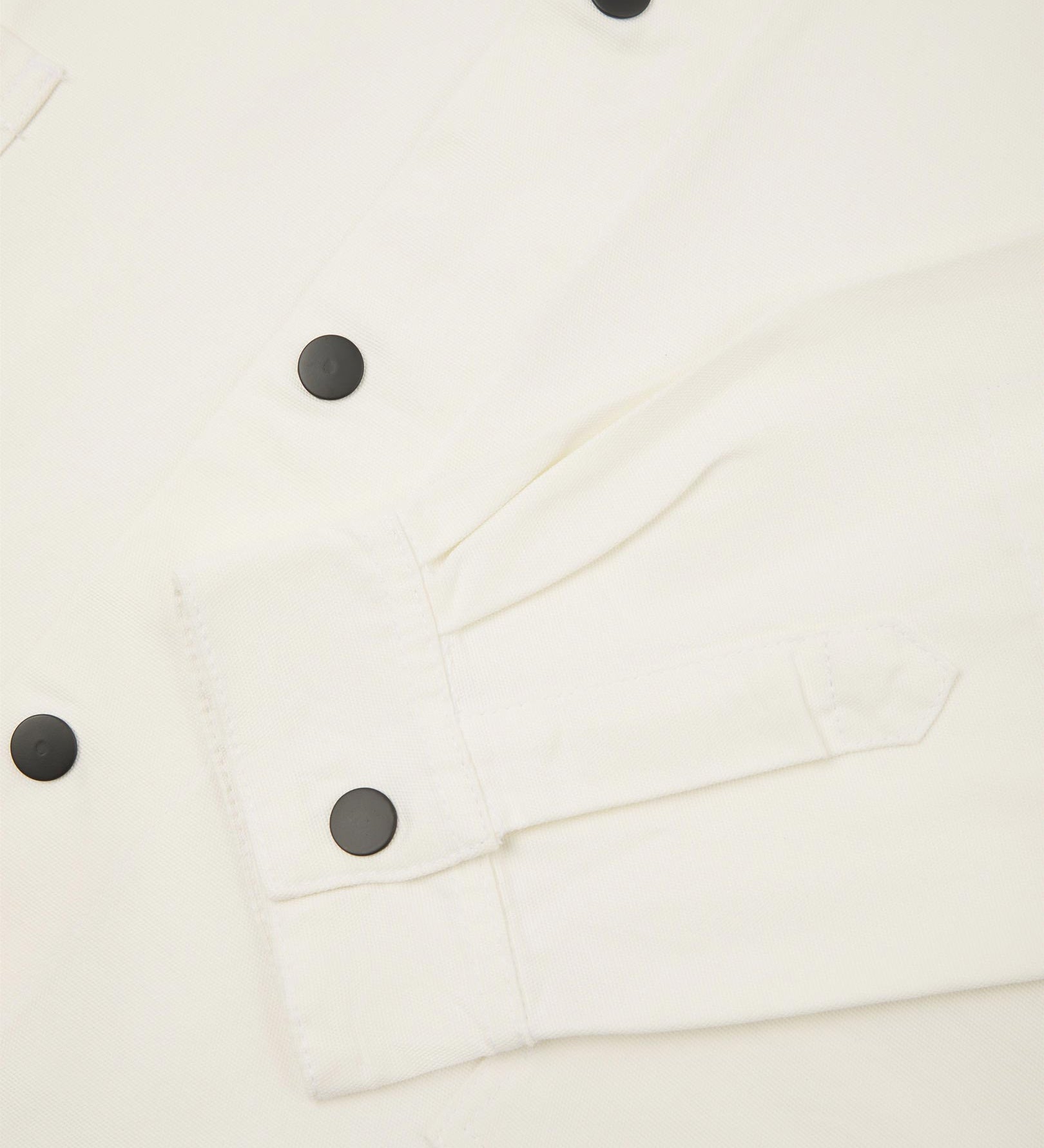 Sleeve view of Uskees 3013 cream organic cotton coach jacket with focus on placket, cuff and popper buttons.