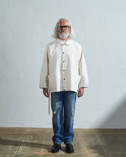 Model front view wearing Uskees Coach's jacket in a discontinued size in cream. Paired with blue jeans.