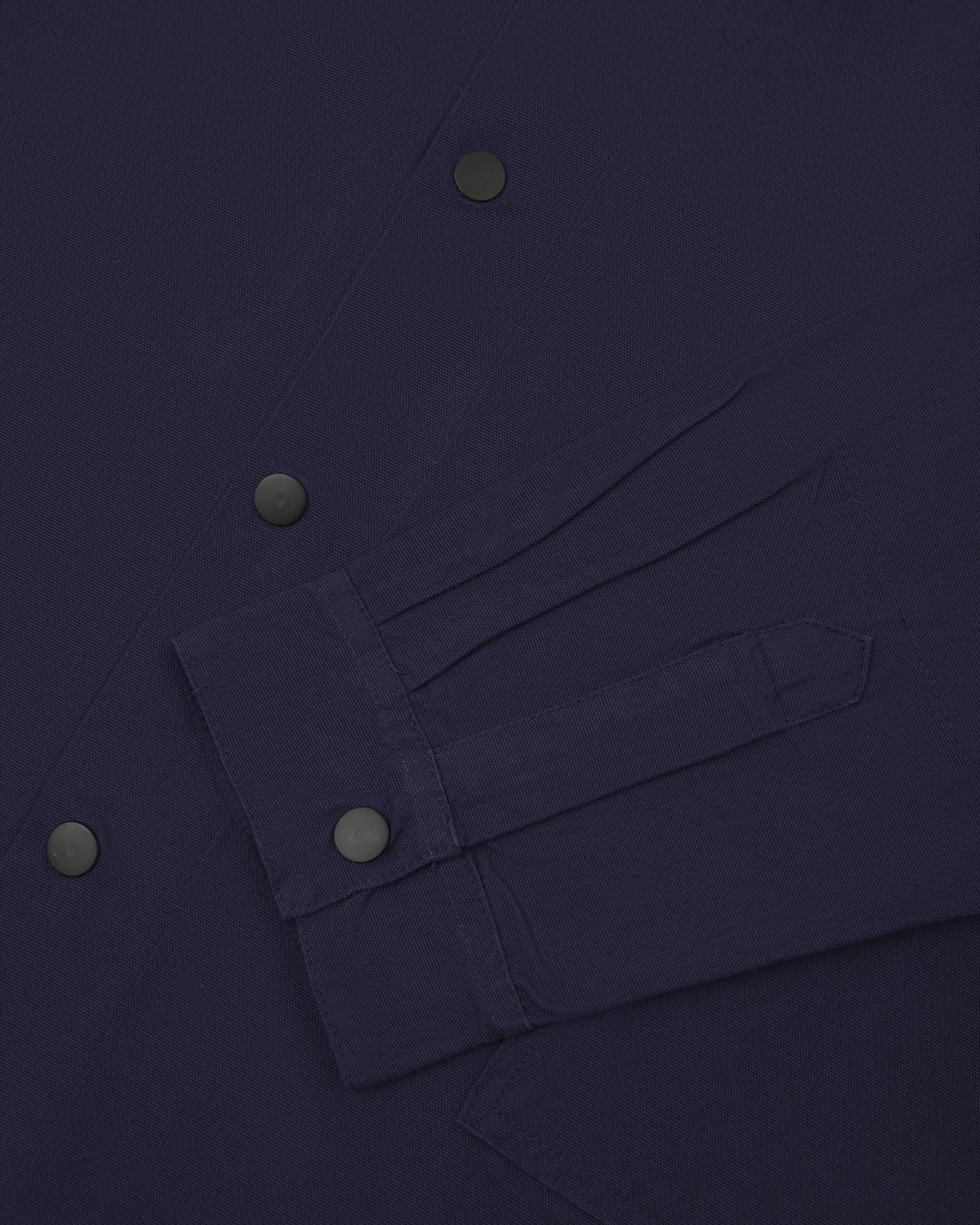 Sleeve view of Uskees 3013 dark blue organic cotton coach jacket with focus on placket, cuff and popper buttons.