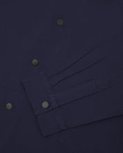 Sleeve view of Uskees 3013 dark blue organic cotton coach jacket with focus on placket, cuff and popper buttons.