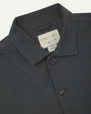 Front close view of charcoal-grey organic cotton drill commuter blazer showing dual collar and Uskees branding label.