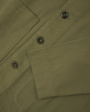 Front close view of moss green organic cotton drill commuter blazer showing cuff/sleeve, corozo buttons & patch pocket