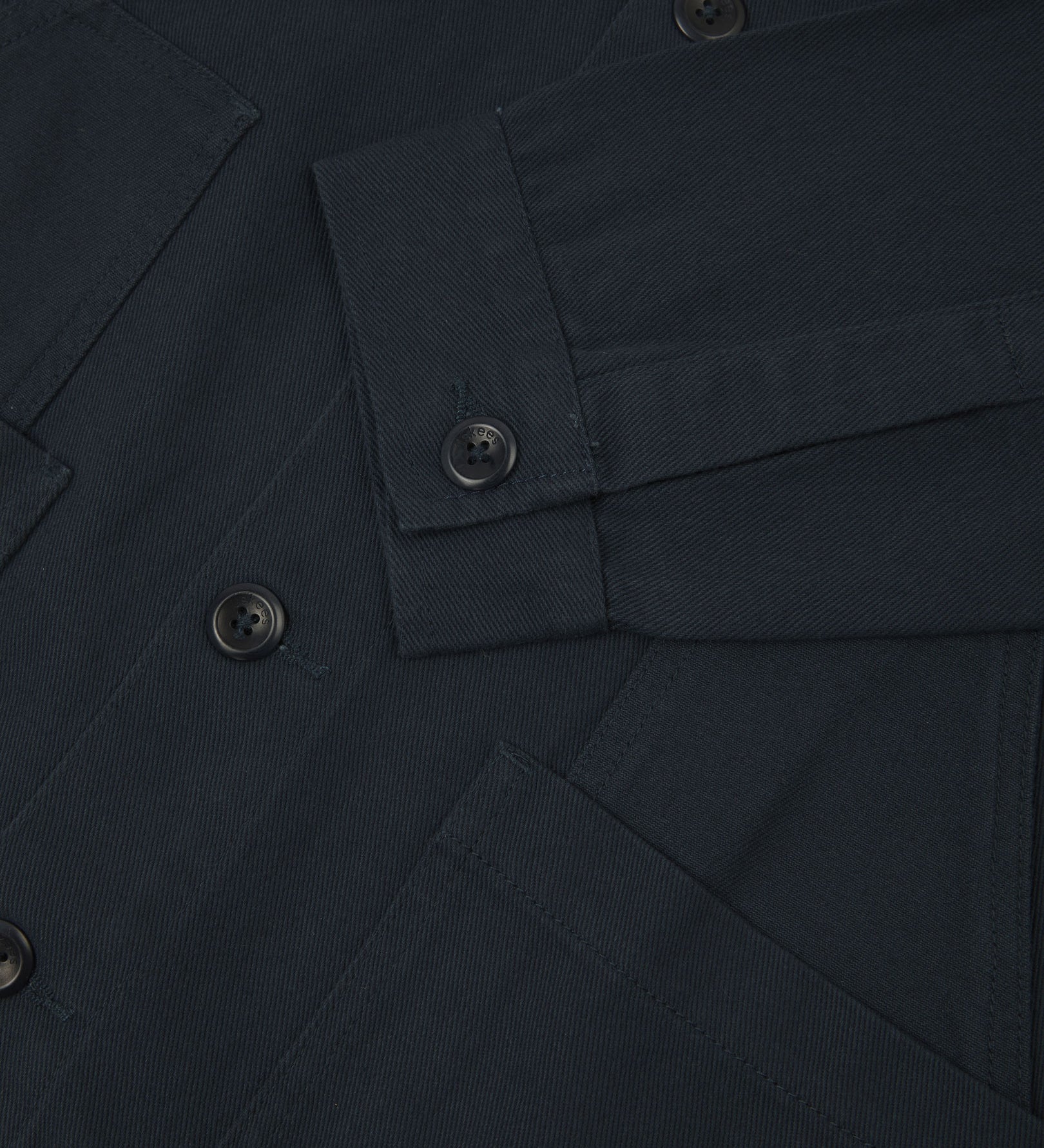 Closer detail view of multiple layered patch pockets, cuff detailing, corozo buttons and extra durable weave of the organic cotton drill fabric.