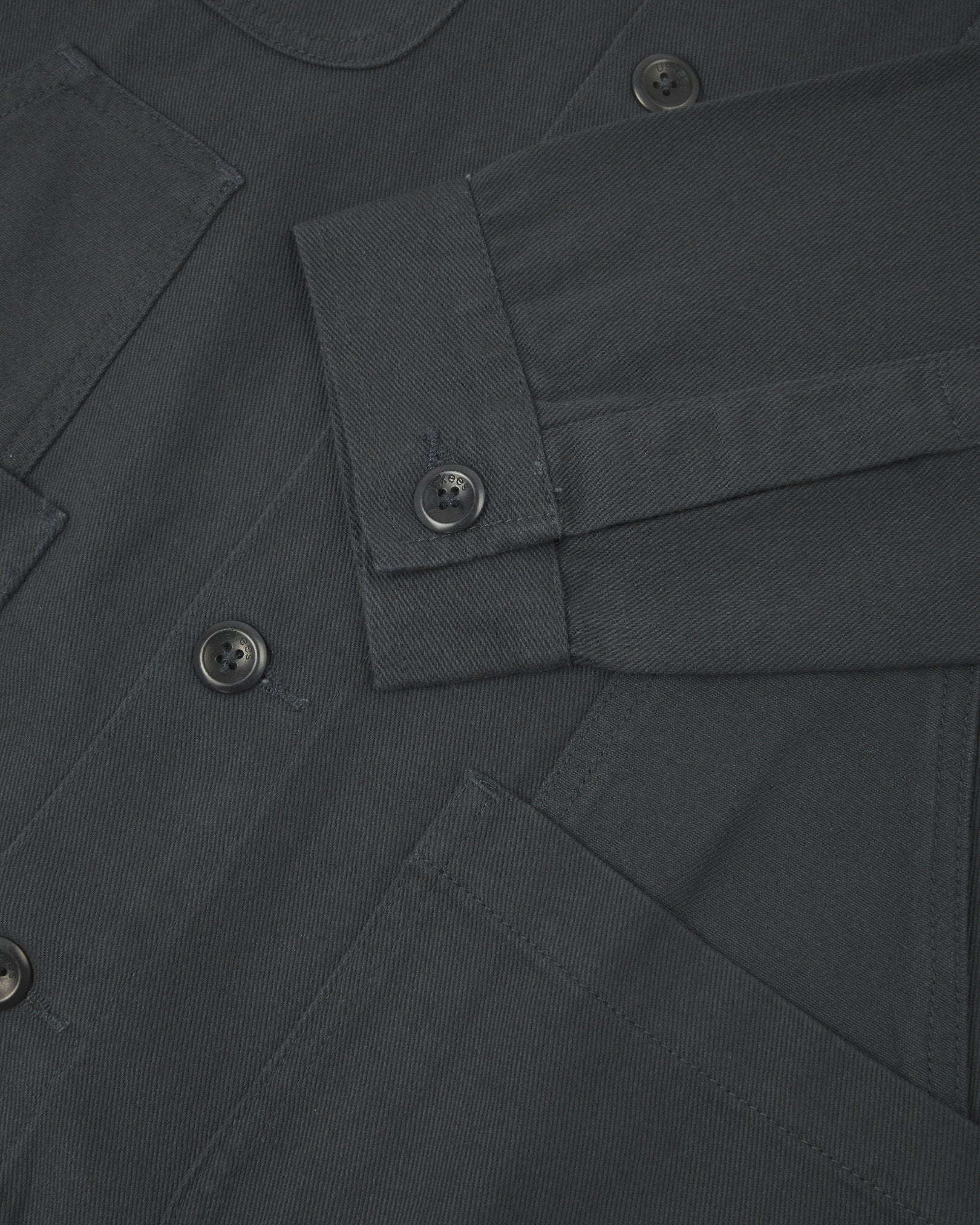 Closer detail view of multi-layered patch pockets, cuff detailing, corozo buttons and extra durable weave of the organic cotton heavyweight drill fabric.