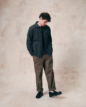 Full length model view of Uskees charcoal-grey drill overshirt with layered pockets. Paired with Uskees khaki pants and dark t-shirt.