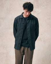 Two-thirds model view of Uskees charcoal-grey drill overshirt with layered pockets. Paired with Uskees khaki pants and dark t-shirt.