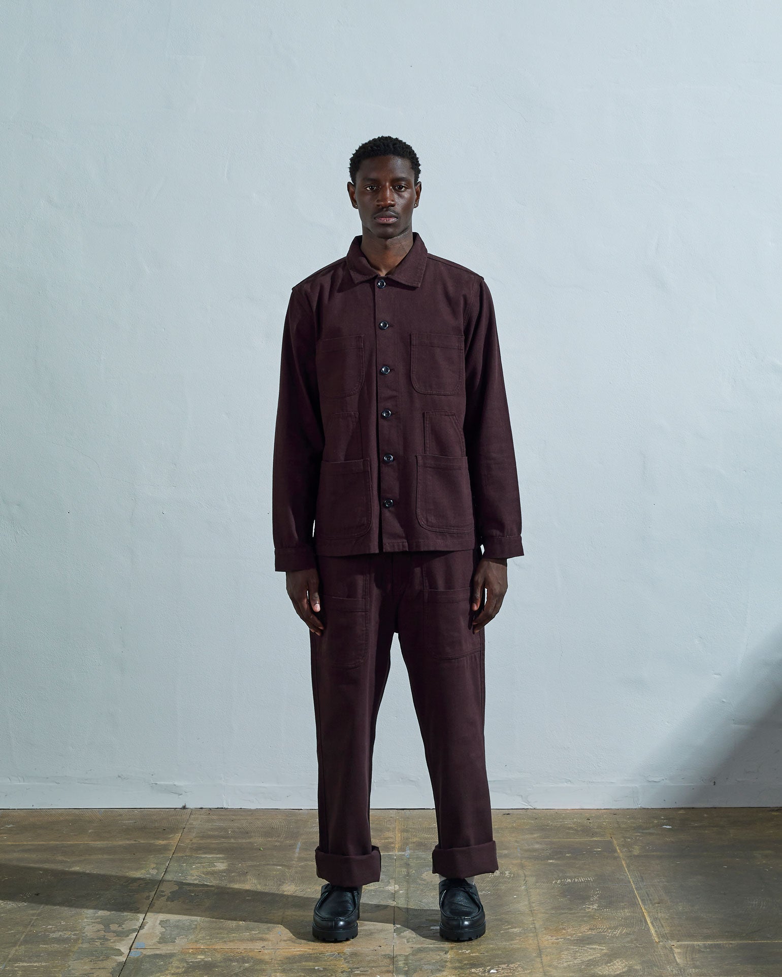 Full-length front view of model wearing #3024 dark plum-coloured organic cotton-drill overshirt paired with matching Uskees pants.