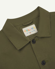 Close up shot of Uskees #3024 drill overshirt in moss showing neck label and Corozo buttons.
