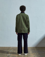Full-length reverse view of model wearing  #3025 coriander-green organic canvas chore jacket, with view of back seam and dark corduroy collar.