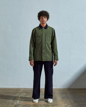 Full-length front view of model wearing fully buttoned #3025 coriander organic canvas chore jacket paired with midnight blue Uskees pants.