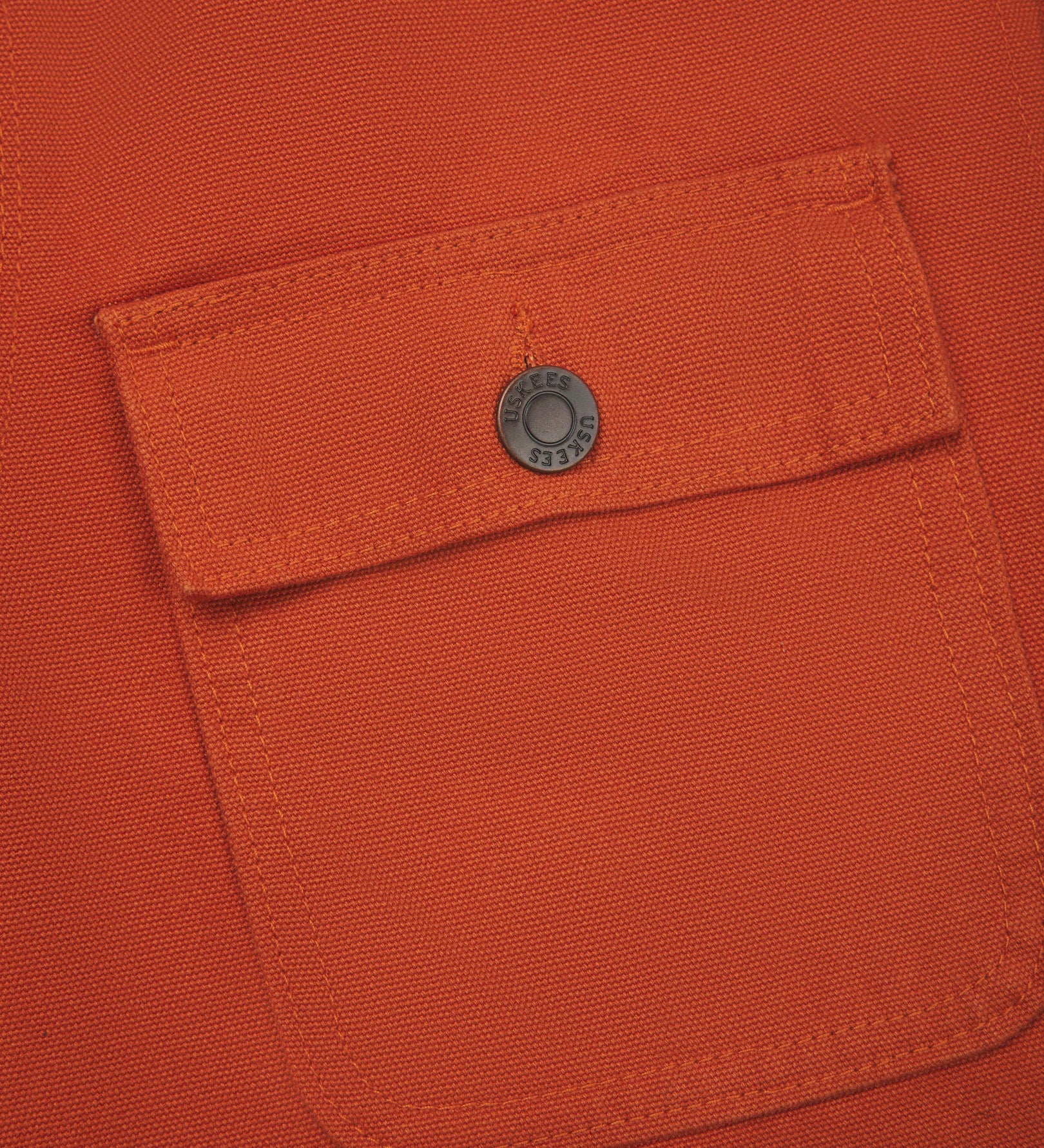 Close-up view of the breast flap pocket on the chest of the 3025 canvas chore jacket, showing a closer look at the metal buttons and the texture of the 510gsm organic cotton canvas.