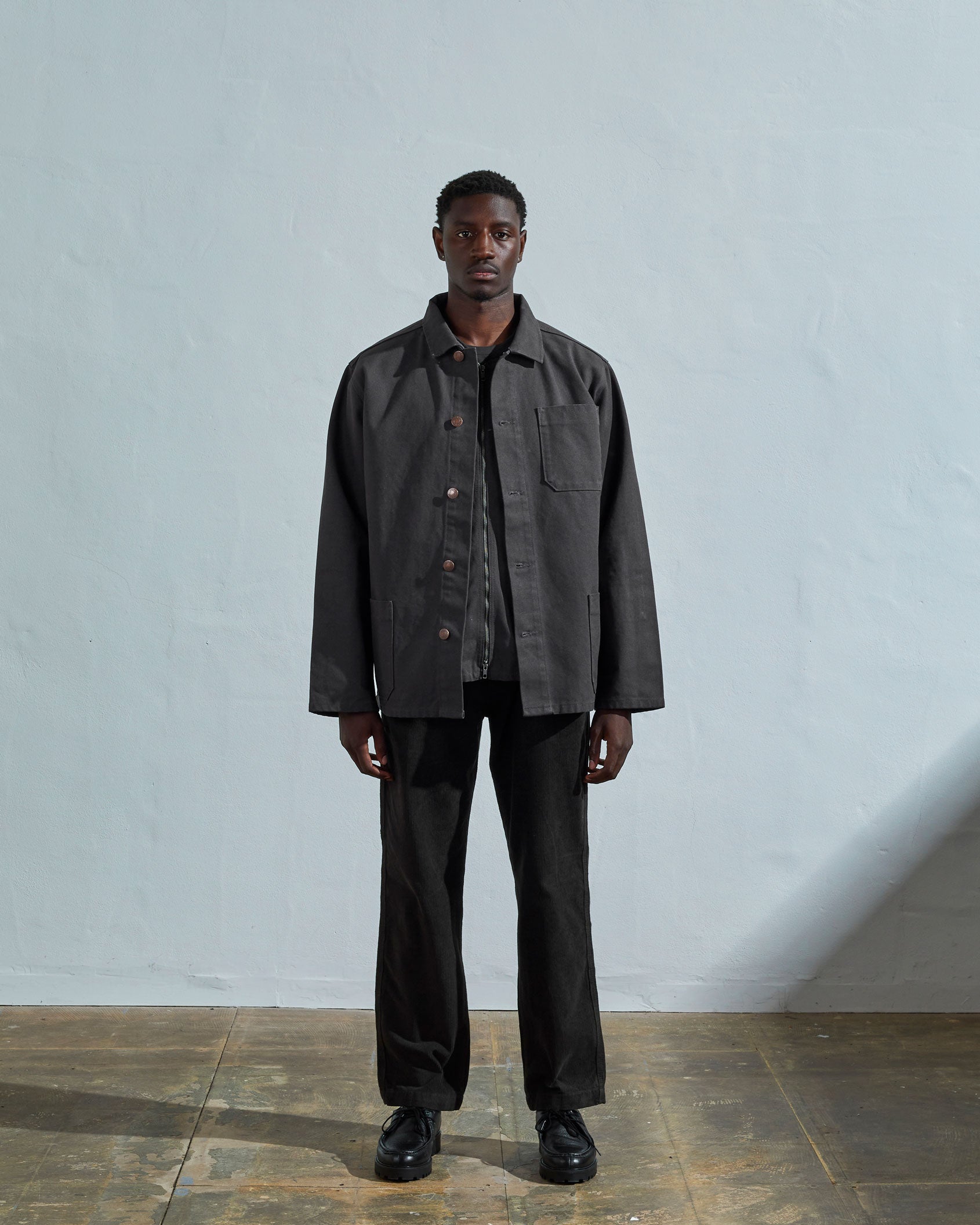 Full-length front view of model wearing #3027 charcoal-coloured organic canvas overshirt with deadstock metal buttons undone.