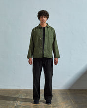 Full-length front view of model wearing #3027 coriander-coloured organic canvas overshirt with deadstock metal buttons undone.